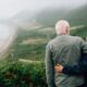 an elderly couple standing together on a hilltop, holding each other