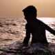 Silhouette of a boy partially submerged in the sea