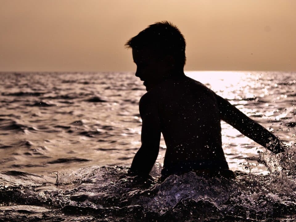 Silhouette of a boy partially submerged in the sea