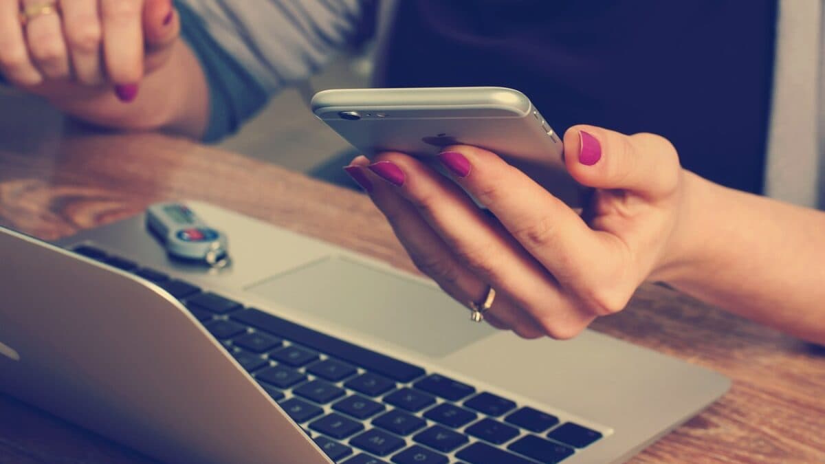 A woman working on her laptop while checking her phone