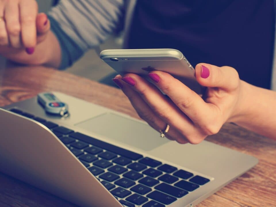 A woman working on her laptop while checking her phone