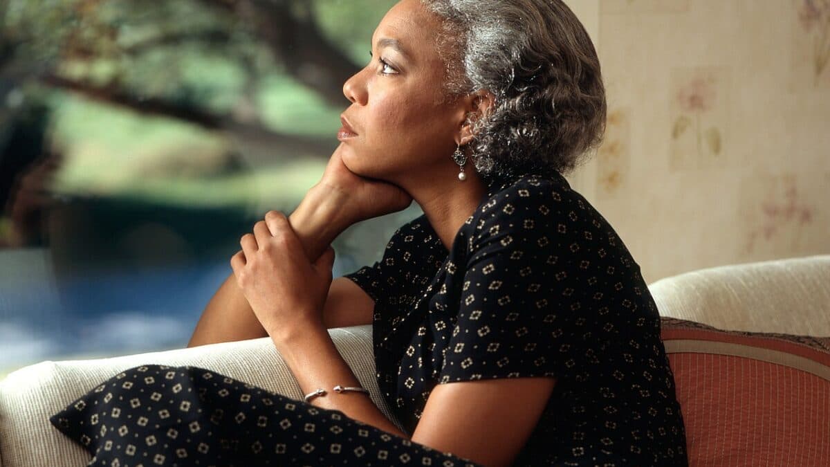 a middle aged woman looking afar while sitting on couch