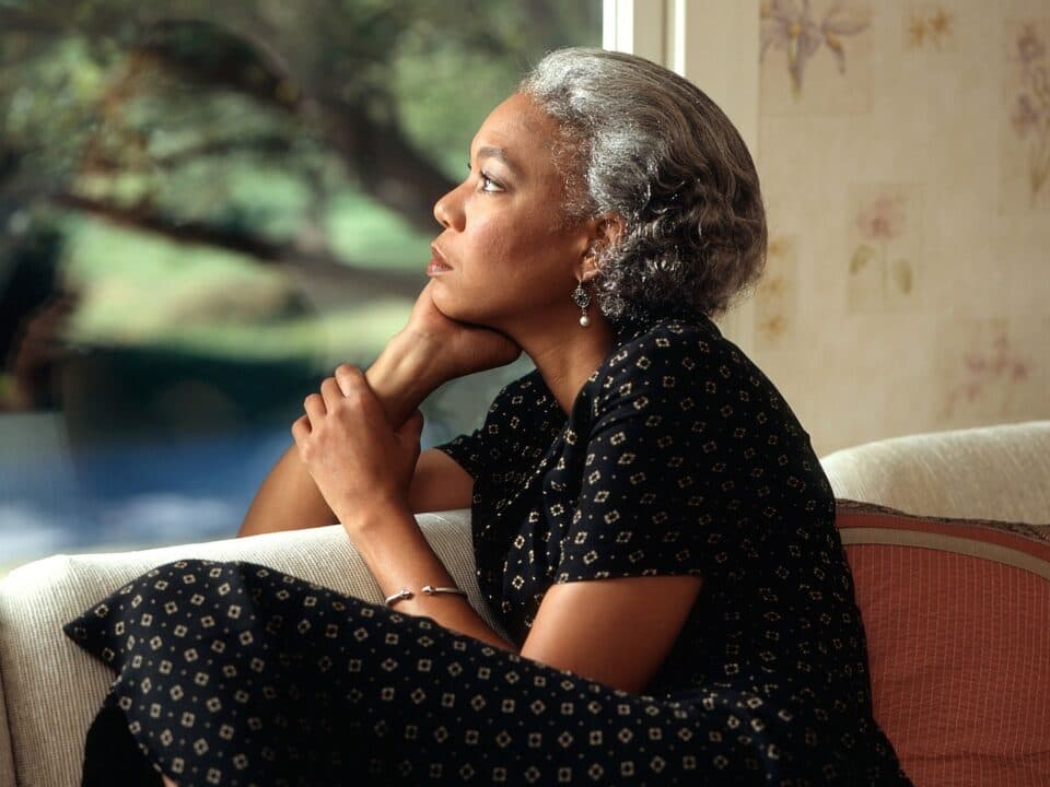 a middle aged woman looking afar while sitting on couch