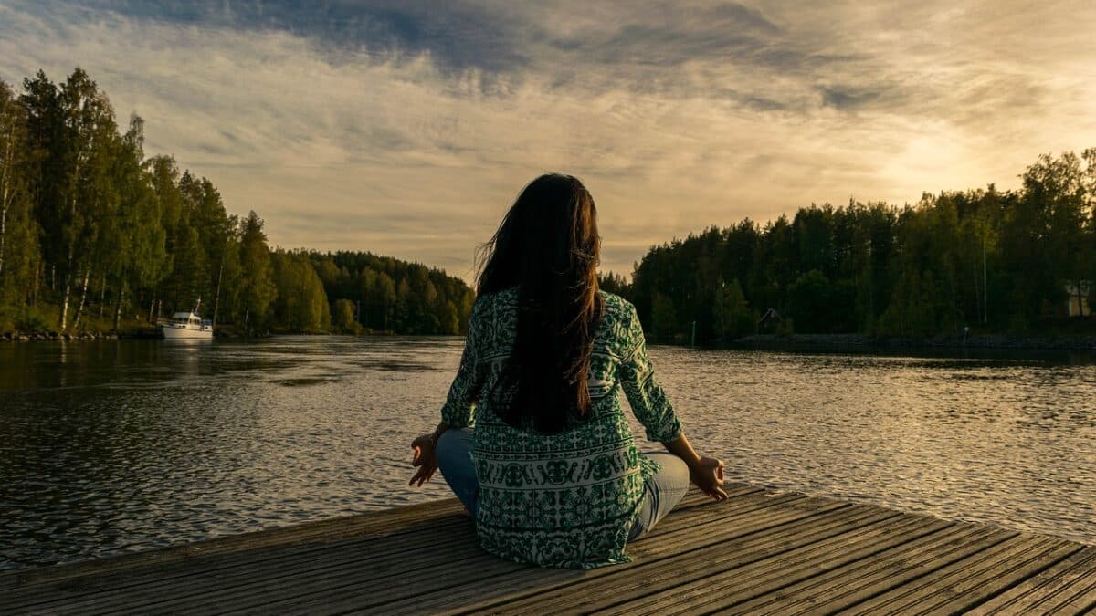 a woman doing yoga on a wooden deck facing a lake