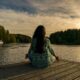 a woman doing yoga on a wooden deck facing a lake