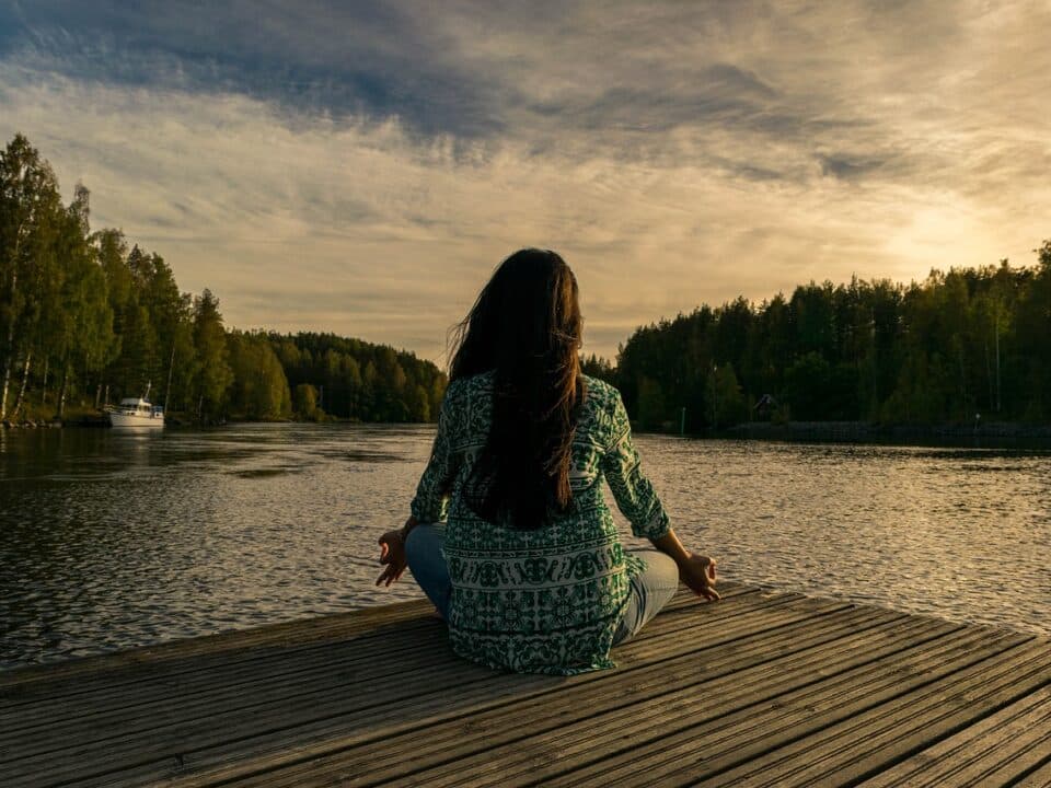 a woman doing yoga on a wooden deck facing a lake