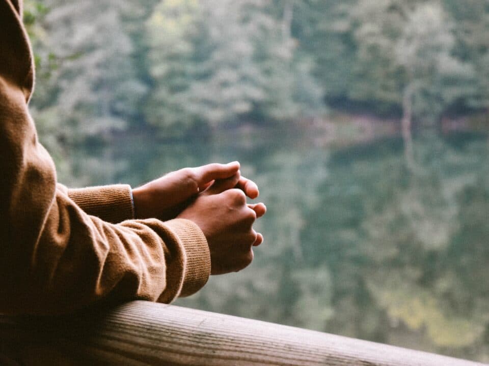 a person resting on a balcony holding both hands