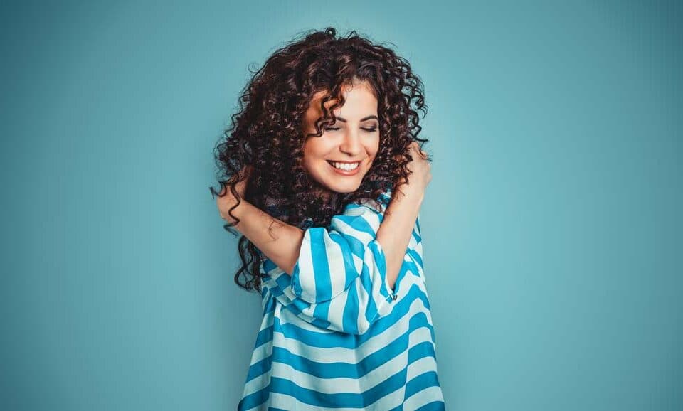 girl with curly hair hugging herself