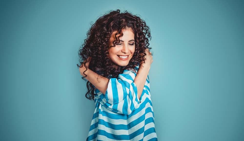 girl with curly hair hugging herself