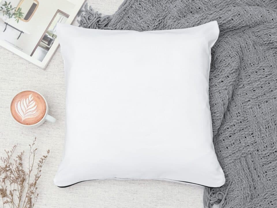 image of pillow on top of blanket with cup of coffee on the side