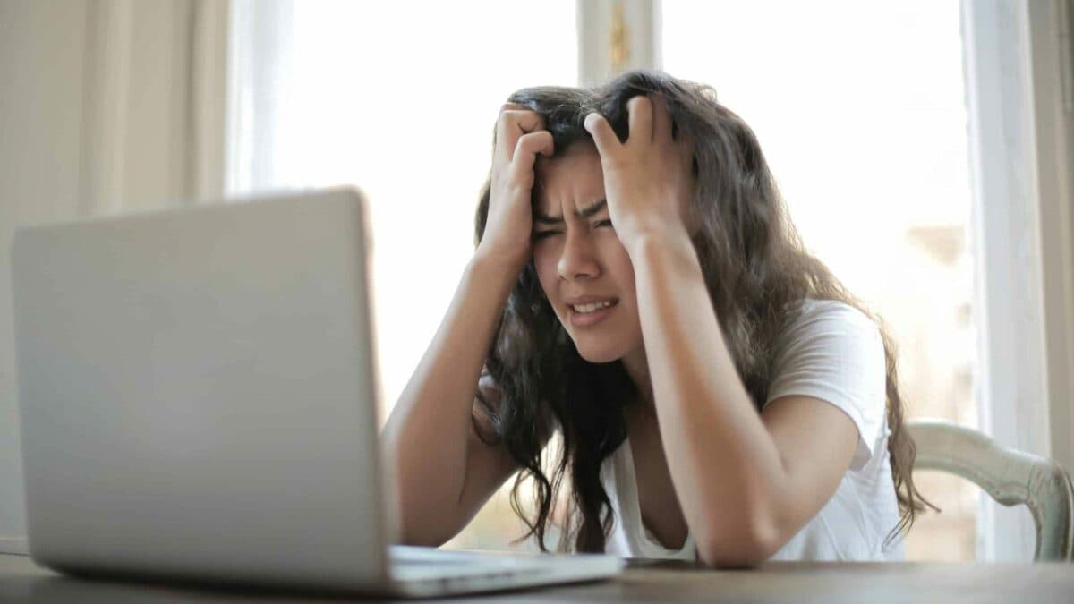 a stressed woman facing a laptop on top of table