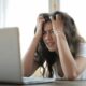 a stressed woman facing a laptop on top of table