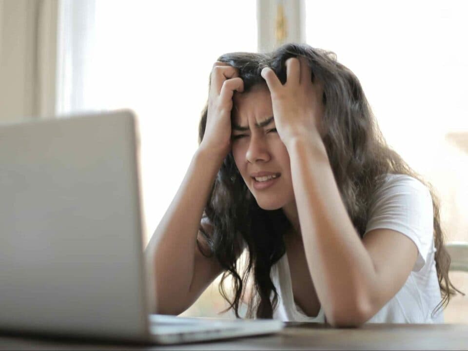 a stressed woman facing a laptop on top of table