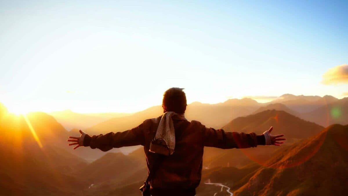 a person feeling the sunset on top of mountains