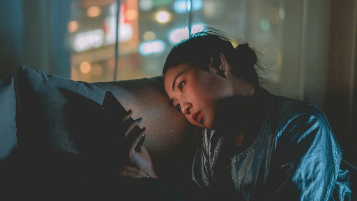 an Asian lady checking on phone in a dark room