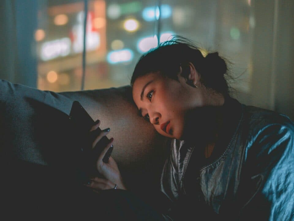 an Asian lady checking on phone in a dark room