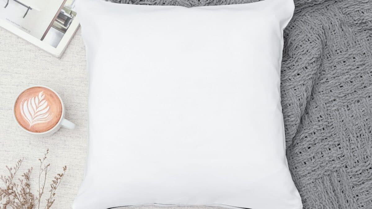 image of pillow on top of blanket with cup of coffee on the side